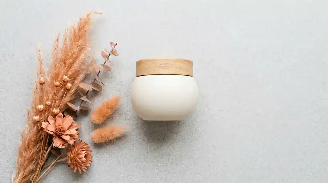 A jar of premium Korean snail cream placed aesthetically among warm terracotta elements and light gray stones.